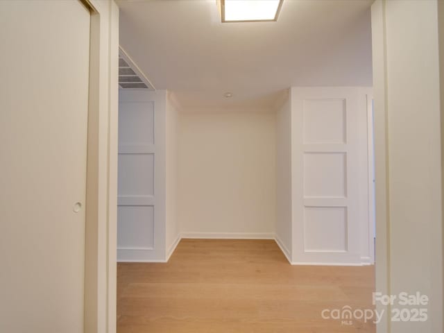 corridor with visible vents, light wood-style flooring, and baseboards