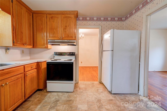 kitchen featuring white appliances, light hardwood / wood-style floors, an inviting chandelier, and sink