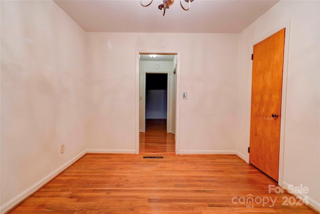 unfurnished room with a chandelier and light hardwood / wood-style floors