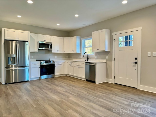 kitchen with white cabinets, stainless steel appliances, and light hardwood / wood-style floors