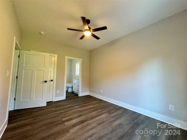 unfurnished bedroom featuring ensuite bathroom, dark hardwood / wood-style floors, and ceiling fan