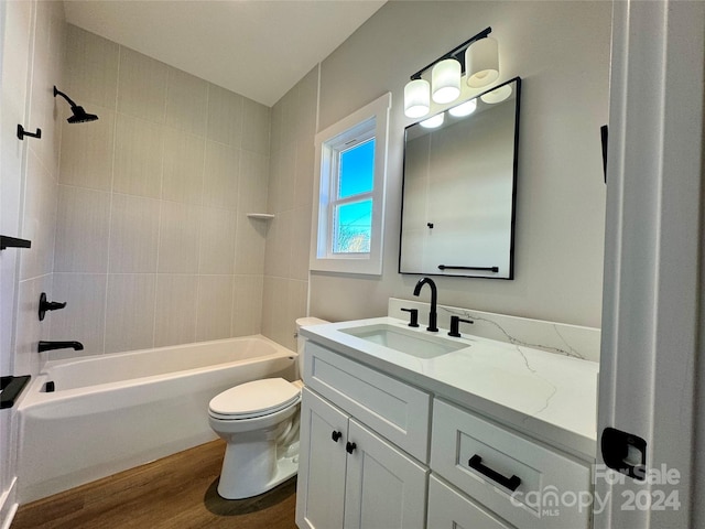 full bathroom featuring hardwood / wood-style floors, vanity, toilet, and tiled shower / bath