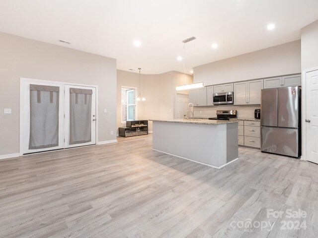 kitchen with a kitchen island with sink, gray cabinets, light wood-type flooring, decorative light fixtures, and stainless steel appliances