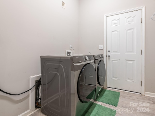 clothes washing area featuring light hardwood / wood-style flooring and washer and dryer