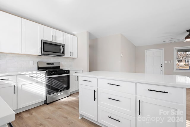 kitchen with white cabinetry, appliances with stainless steel finishes, decorative backsplash, a kitchen island, and light wood-type flooring