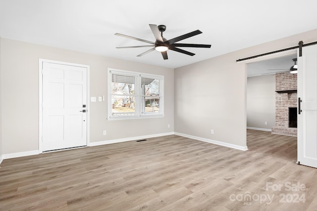 interior space featuring ceiling fan, a fireplace, and light hardwood / wood-style flooring