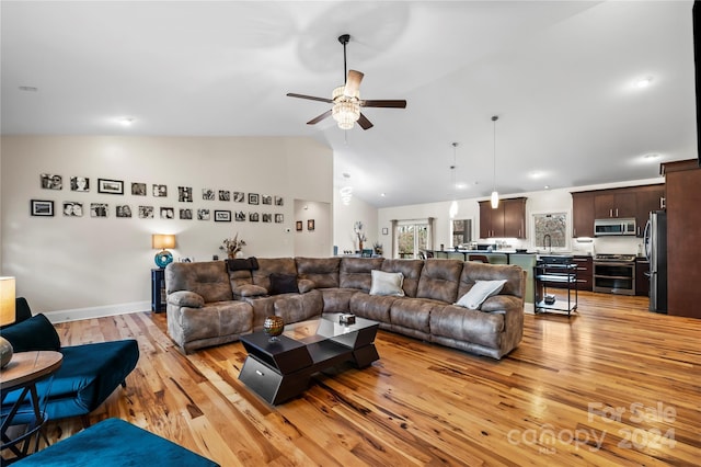 living room featuring light hardwood / wood-style floors, vaulted ceiling, ceiling fan, and sink