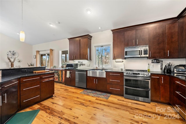 kitchen with dark brown cabinetry, sink, stainless steel appliances, light hardwood / wood-style flooring, and decorative light fixtures