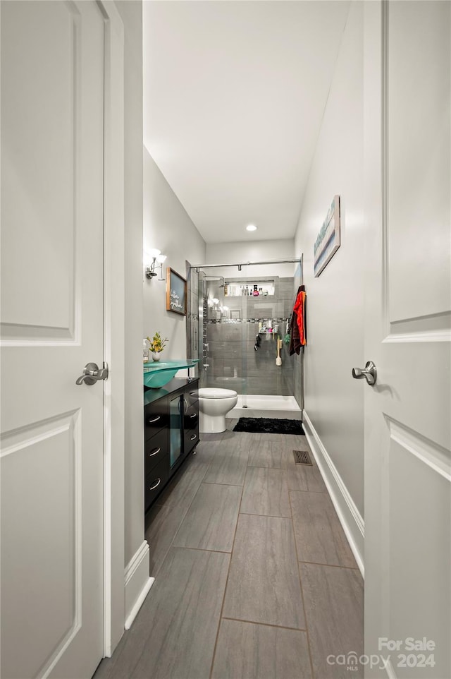 bathroom with hardwood / wood-style flooring, vanity, and a tile shower