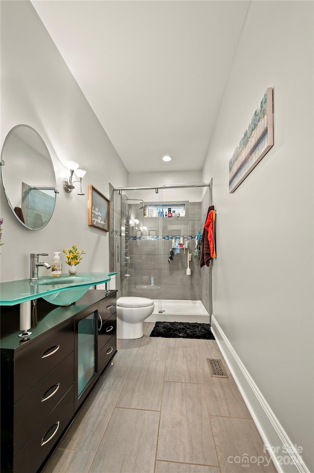 bathroom with vanity, toilet, and a shower with door