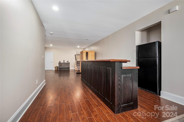 interior space with dark brown cabinetry, black fridge, and dark hardwood / wood-style floors