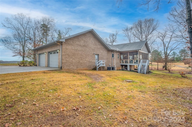 view of side of home with a sunroom, a garage, and a lawn