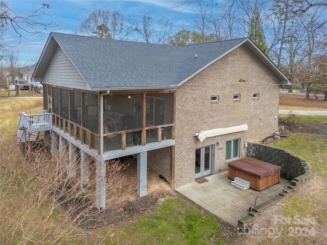 rear view of house featuring a sunroom, a patio, and a hot tub