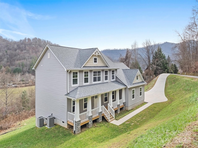 view of front of house featuring a mountain view, covered porch, central air condition unit, and a front yard