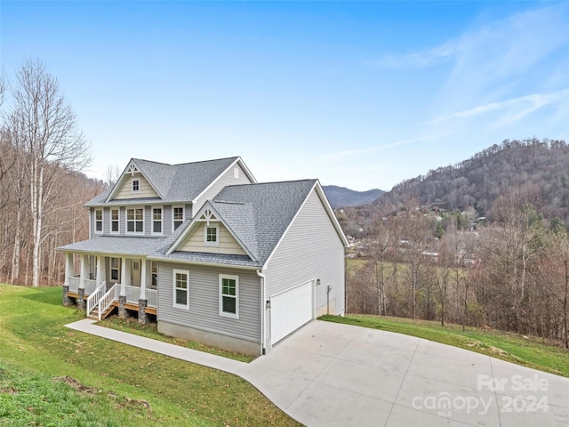 view of front of house featuring a mountain view, a front yard, a garage, and covered porch