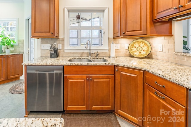 kitchen with backsplash, sink, stainless steel dishwasher, light stone countertops, and light tile patterned floors