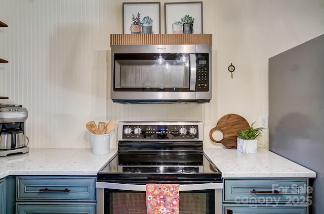 kitchen featuring light stone counters, blue cabinets, and appliances with stainless steel finishes