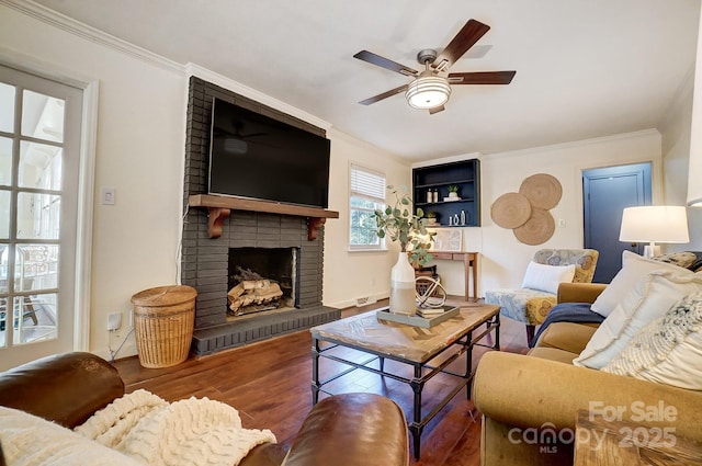 living room with hardwood / wood-style floors, ceiling fan, ornamental molding, and a fireplace