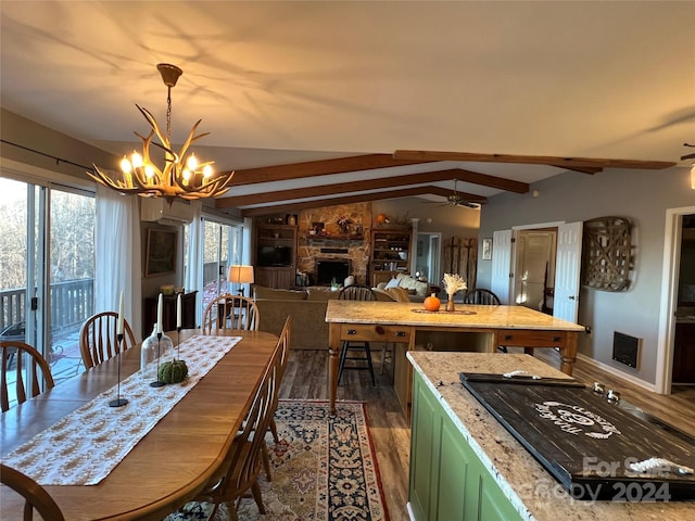 dining area with a stone fireplace, dark wood-type flooring, lofted ceiling with beams, and ceiling fan with notable chandelier