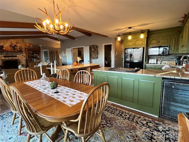 dining area with lofted ceiling with beams, sink, wine cooler, a fireplace, and a chandelier