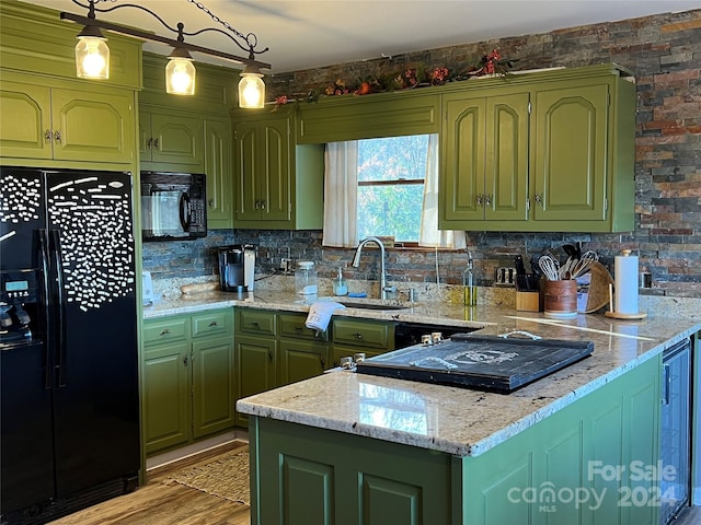 kitchen with light stone countertops, light hardwood / wood-style flooring, decorative light fixtures, black appliances, and green cabinetry