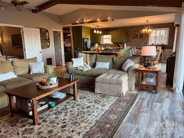 living room featuring vaulted ceiling with beams, light wood-type flooring, and ceiling fan with notable chandelier