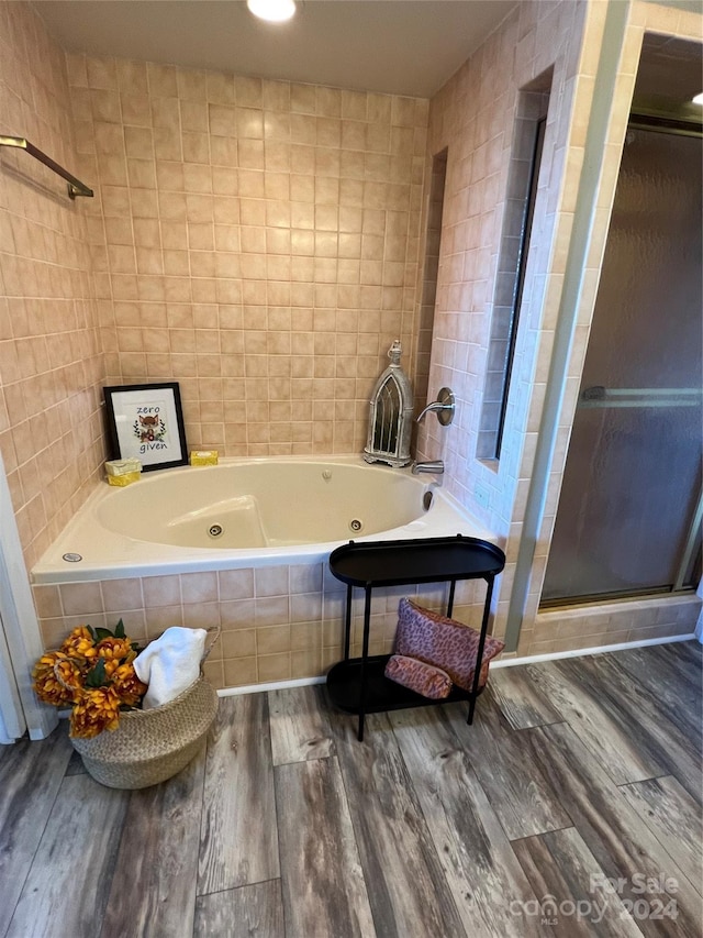 bathroom with hardwood / wood-style floors, shower with separate bathtub, and tile walls