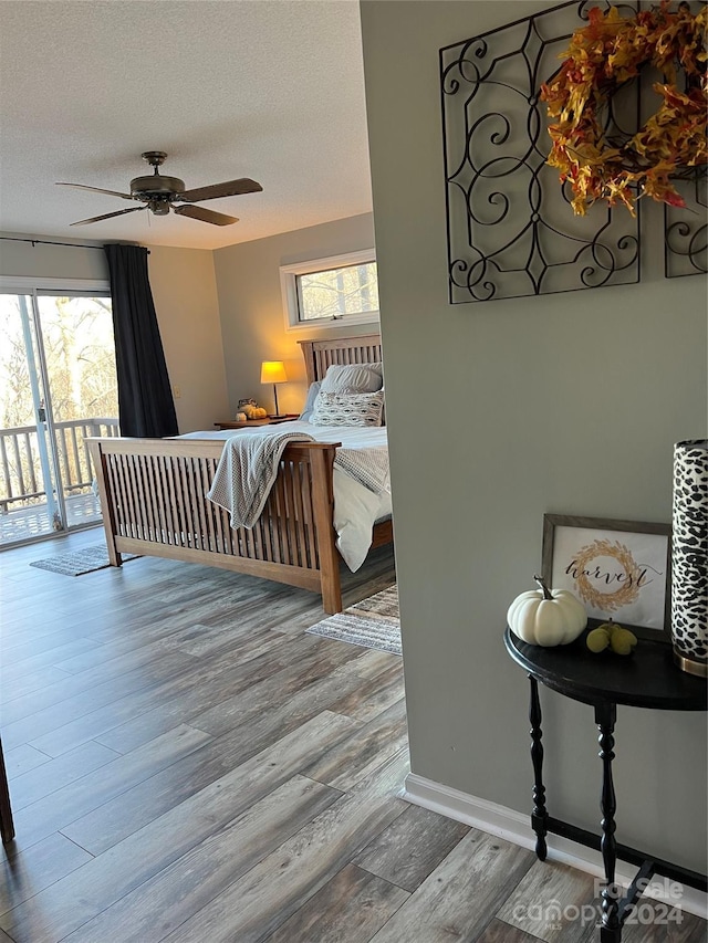 bedroom with hardwood / wood-style flooring, ceiling fan, access to exterior, and a textured ceiling