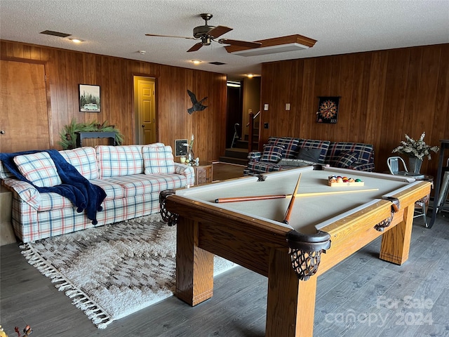 recreation room with hardwood / wood-style flooring, ceiling fan, wood walls, and a textured ceiling