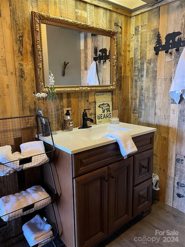 bathroom featuring hardwood / wood-style flooring, vanity, and wood walls