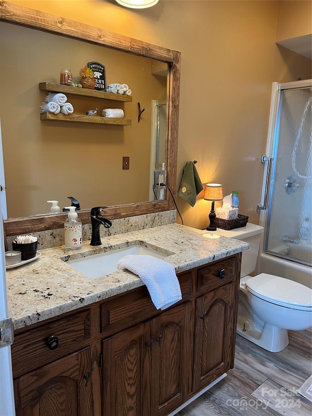 full bathroom with hardwood / wood-style floors, vanity, toilet, and enclosed tub / shower combo