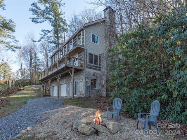 exterior space with a balcony, a garage, and an outdoor fire pit