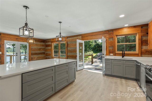 kitchen with french doors, sink, wood walls, decorative light fixtures, and gray cabinets