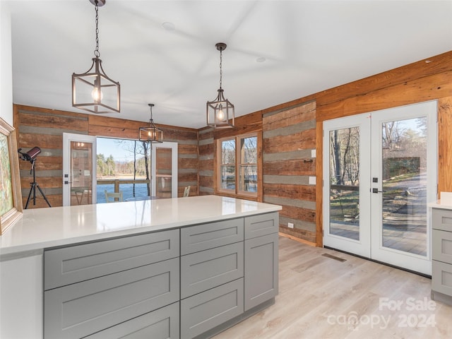 kitchen featuring french doors, light wood-type flooring, gray cabinetry, and wood walls