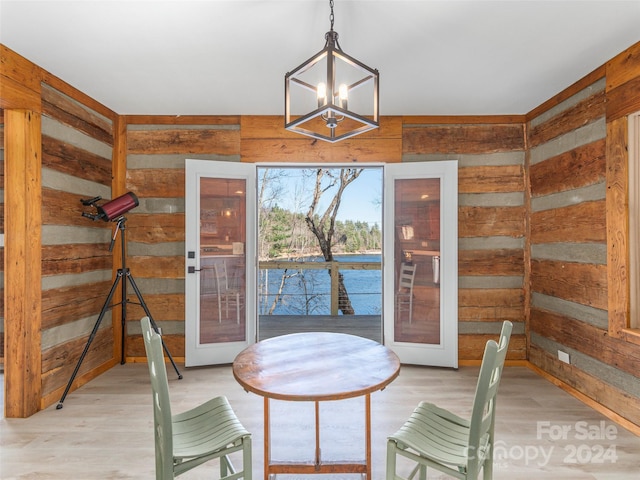 unfurnished dining area with wood walls, light hardwood / wood-style flooring, and french doors