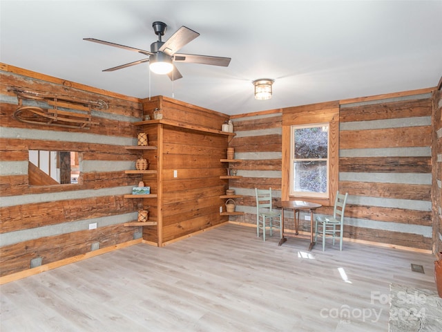 interior space featuring wood walls, ceiling fan, and light hardwood / wood-style floors