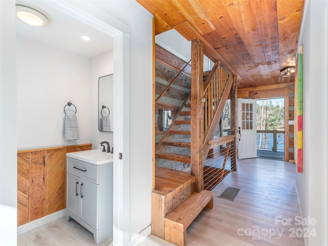 staircase with wood-type flooring, wood walls, and sink