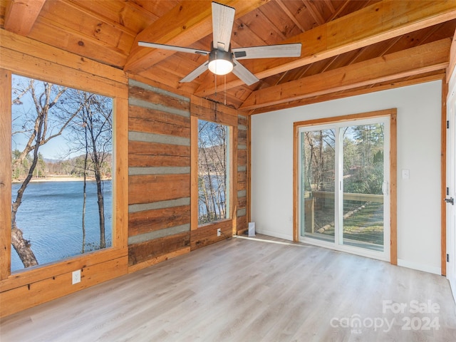 unfurnished sunroom featuring lofted ceiling with beams, ceiling fan, a water view, and wood ceiling