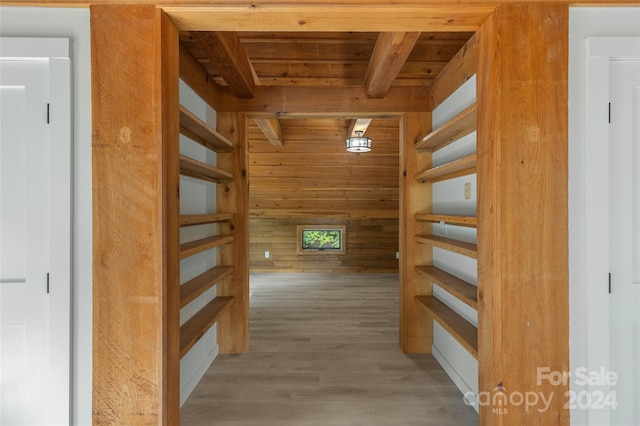 corridor featuring beam ceiling, wooden walls, wooden ceiling, and hardwood / wood-style flooring