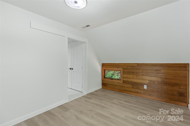 additional living space with light hardwood / wood-style flooring and vaulted ceiling