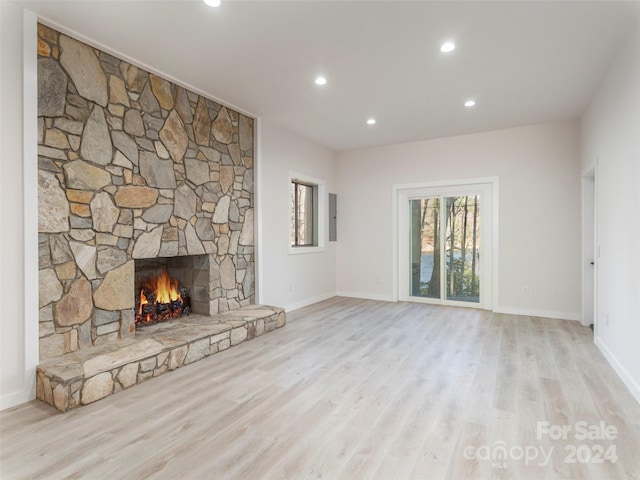 unfurnished living room with a stone fireplace and light hardwood / wood-style floors