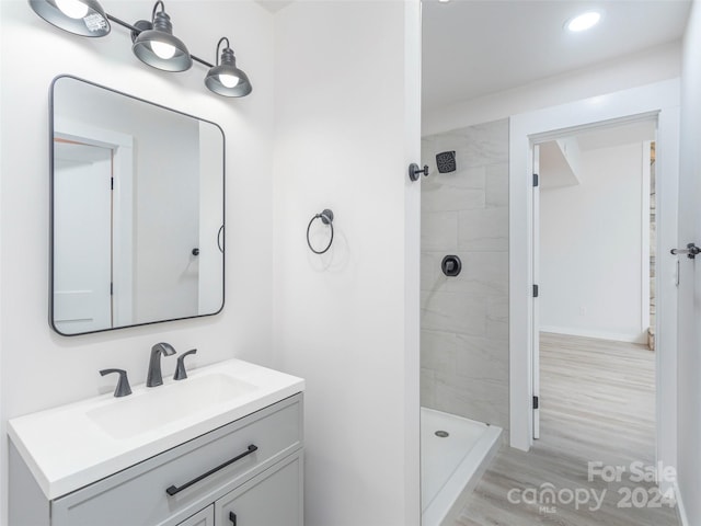 bathroom featuring hardwood / wood-style floors, vanity, and tiled shower