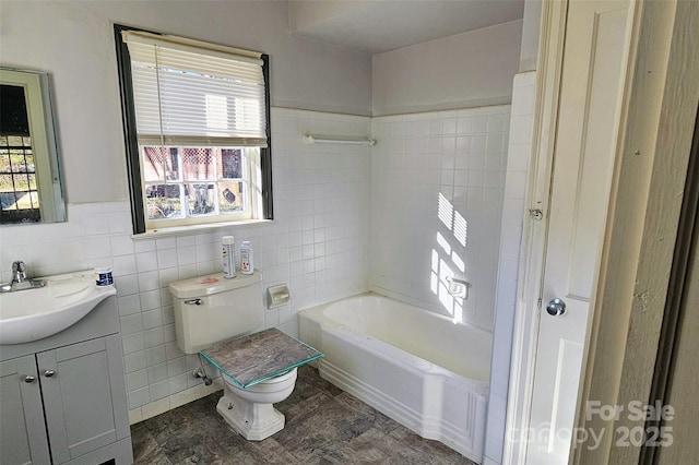 bathroom featuring vanity, toilet, tile walls, and a washtub