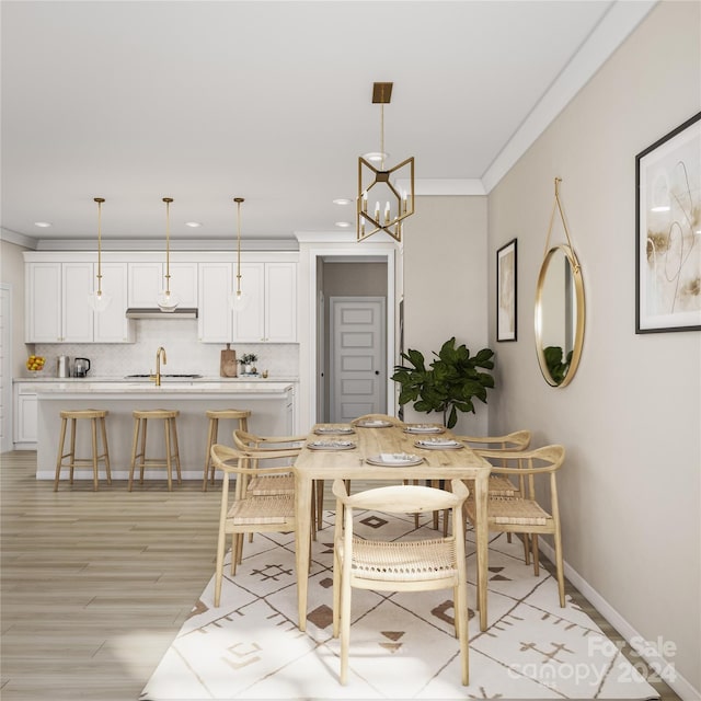 dining space with ornamental molding, light wood-type flooring, and a notable chandelier