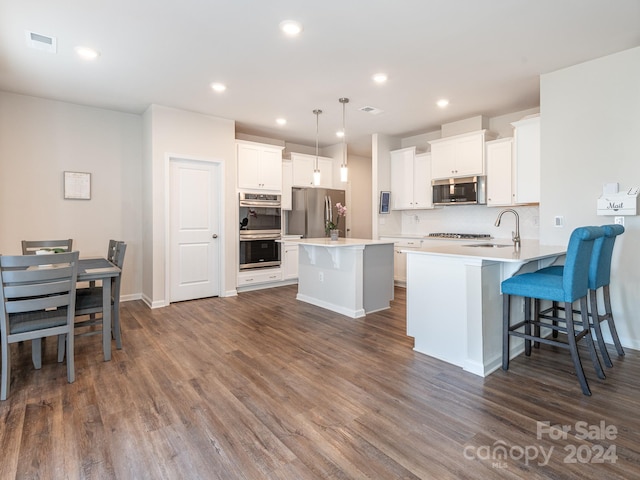 kitchen featuring dark wood-type flooring, white cabinets, hanging light fixtures, and appliances with stainless steel finishes