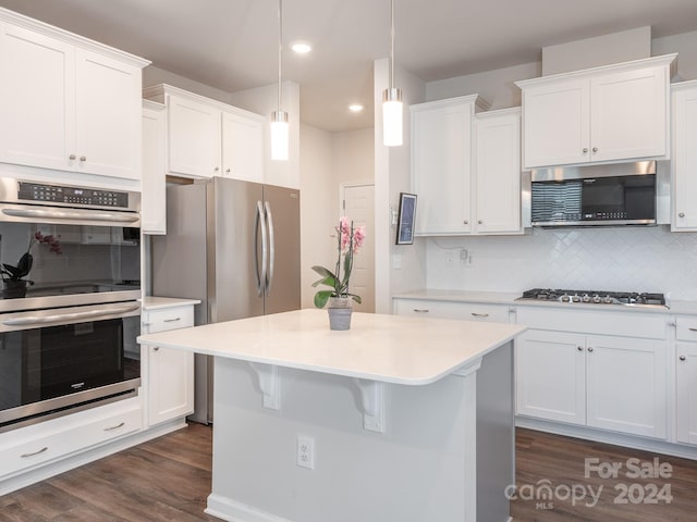 kitchen featuring dark wood-type flooring, white cabinets, hanging light fixtures, appliances with stainless steel finishes, and tasteful backsplash