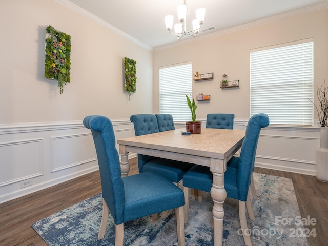 dining area with ornamental molding, dark wood-type flooring, and an inviting chandelier