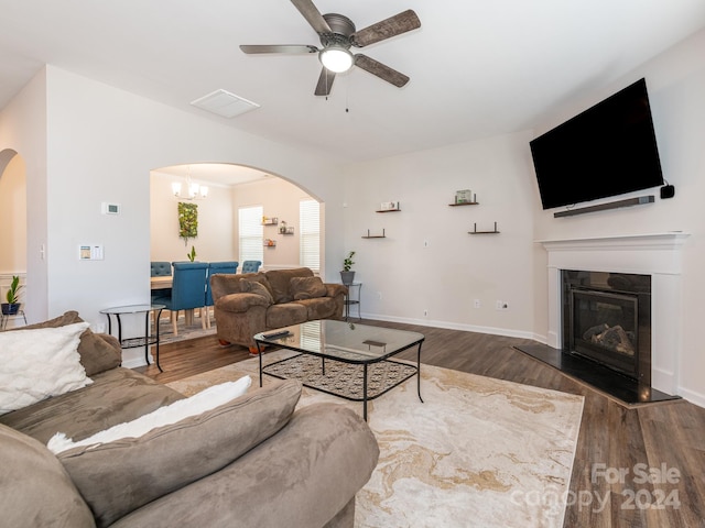 living room with ceiling fan with notable chandelier and dark hardwood / wood-style flooring