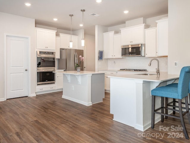 kitchen with a kitchen breakfast bar, white cabinets, stainless steel appliances, and dark hardwood / wood-style floors