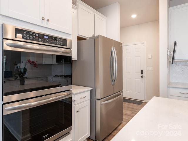 kitchen featuring stainless steel appliances, white cabinetry, tasteful backsplash, and light hardwood / wood-style flooring